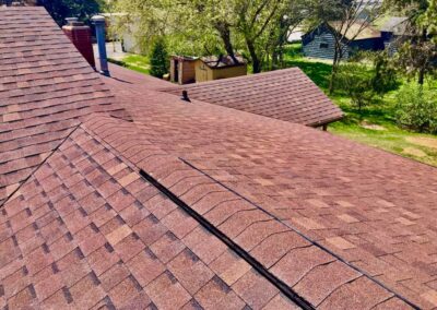 Residential asphalt roof replacement completed with red architectural shingles