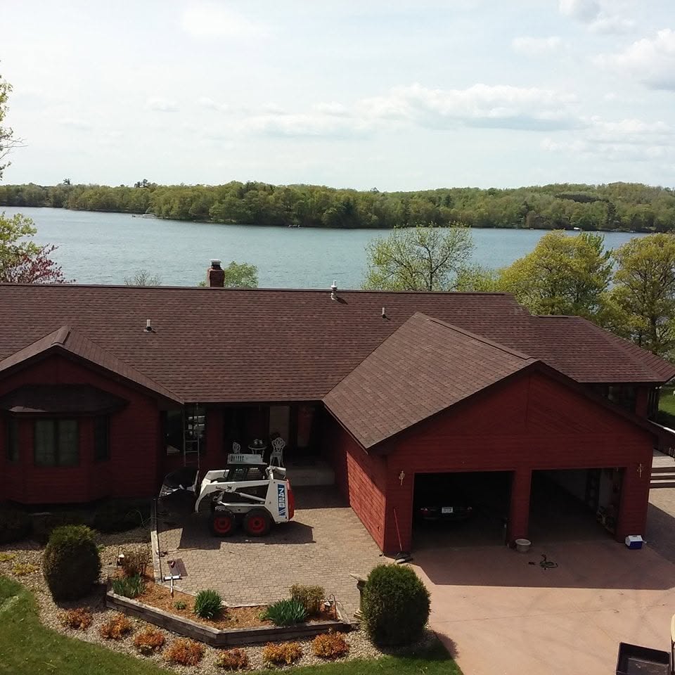 Residential asphalt roof replacement completed red shingles air view