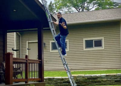 Robert Aguirre climbing ladder to work on residential asphalt shingles roof project