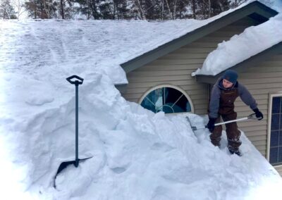 Heavy roof snow load on residential home and snow removal in progress